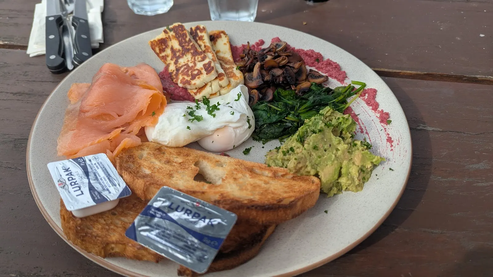 A breakfast plate with smoked salmon, haloumi, eggs, avocado and toast